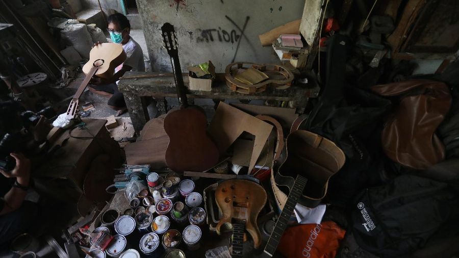 Pengrajjn  memperbaiki gitar pelanggan di servis gitar pak Manto, Jakarta Selatan, Senin (8/2/2021). Selain mereparasi gitar, Manto juga memproduksi gitar akustik yang dijual dari harga ratusan ribu hingga juta, tergantung jenis dan tingkat kesulitannya. (CNBC Indonesia/Andrean Kristianto)