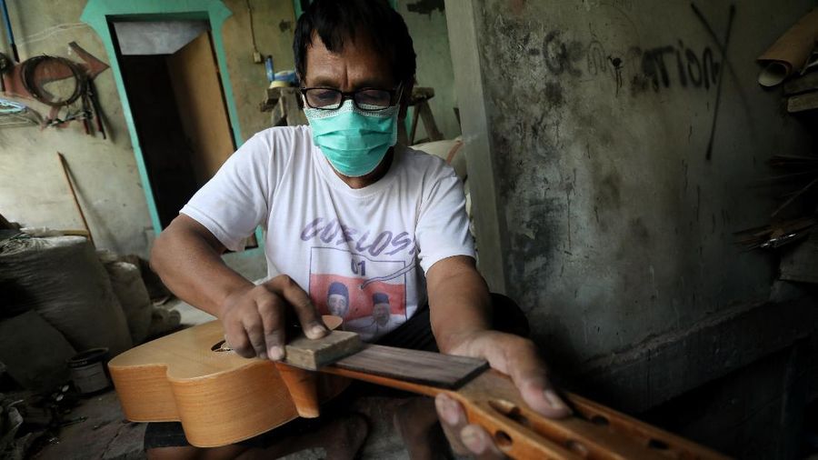 Pengrajjn  memperbaiki gitar pelanggan di servis gitar pak Manto, Jakarta Selatan, Senin (8/2/2021). Selain mereparasi gitar, Manto juga memproduksi gitar akustik yang dijual dari harga ratusan ribu hingga juta, tergantung jenis dan tingkat kesulitannya. (CNBC Indonesia/Andrean Kristianto)
