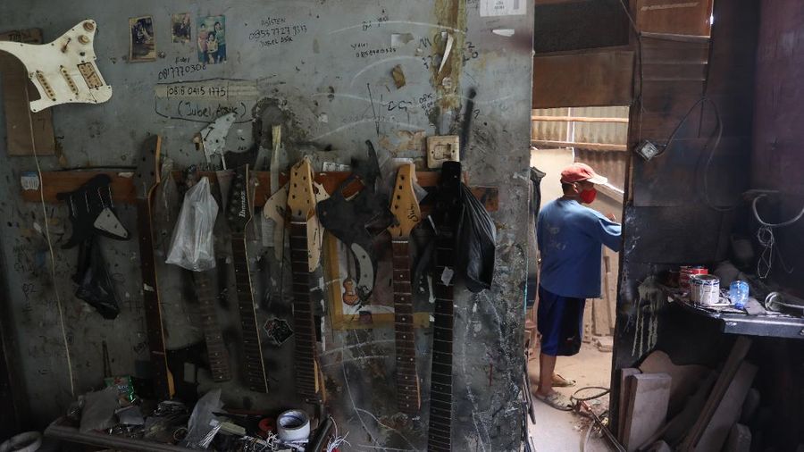 Pengrajjn  memperbaiki gitar pelanggan di servis gitar pak Manto, Jakarta Selatan, Senin (8/2/2021). Selain mereparasi gitar, Manto juga memproduksi gitar akustik yang dijual dari harga ratusan ribu hingga juta, tergantung jenis dan tingkat kesulitannya. (CNBC Indonesia/Andrean Kristianto)