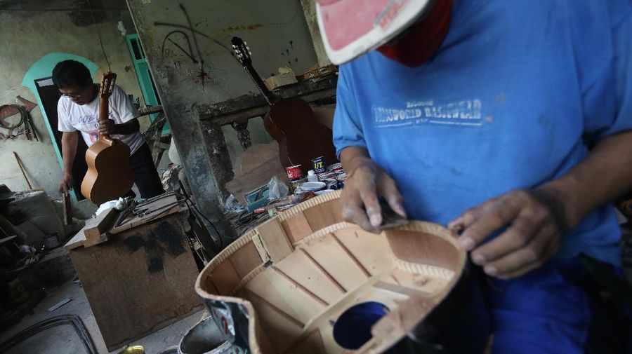 Pengrajjn  memperbaiki gitar pelanggan di servis gitar pak Manto, Jakarta Selatan, Senin (8/2/2021). Selain mereparasi gitar, Manto juga memproduksi gitar akustik yang dijual dari harga ratusan ribu hingga juta, tergantung jenis dan tingkat kesulitannya. (CNBC Indonesia/Andrean Kristianto)