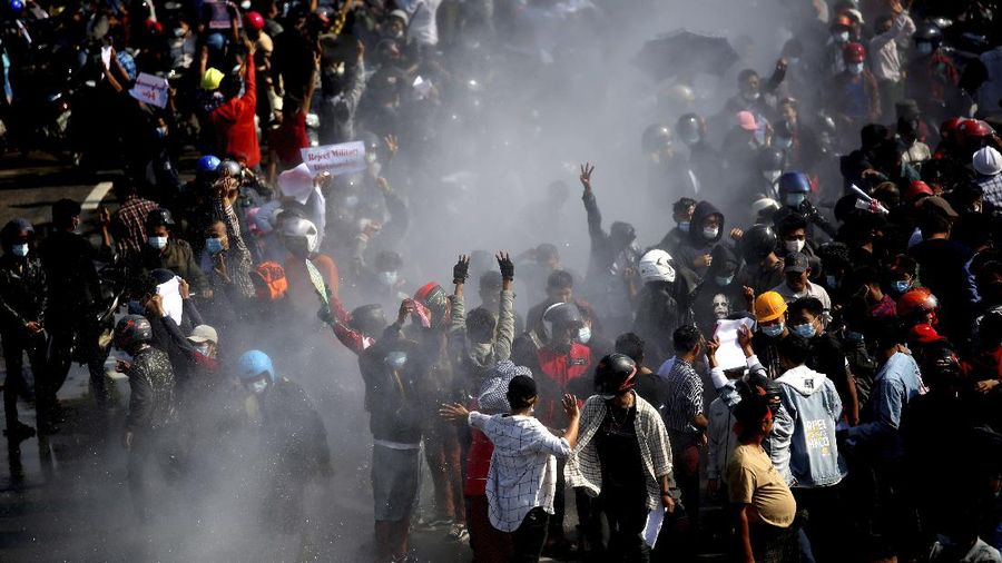 Protesters are sprayed with water fired from a police truck's water cannon in Naypyitaw, Myanmar on Monday, Feb. 8, 2021. Tension in the confrontations between the authorities and demonstrators against last week's coup in Myanmar boiled over Monday, as police fired a water cannon at peaceful protesters in the capital Naypyitaw.(AP Photo)