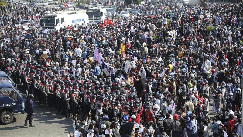 Protesters are sprayed with water fired from a police truck's water cannon in Naypyitaw, Myanmar on Monday, Feb. 8, 2021. Tension in the confrontations between the authorities and demonstrators against last week's coup in Myanmar boiled over Monday, as police fired a water cannon at peaceful protesters in the capital Naypyitaw.(AP Photo)