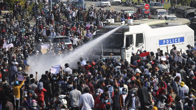 Protesters are sprayed with water fired from a police truck's water cannon in Naypyitaw, Myanmar on Monday, Feb. 8, 2021. Tension in the confrontations between the authorities and demonstrators against last week's coup in Myanmar boiled over Monday, as police fired a water cannon at peaceful protesters in the capital Naypyitaw.(AP Photo)