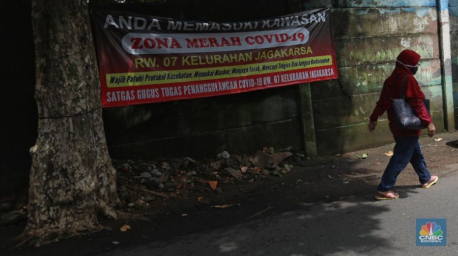 Warga melintas di wilayah Zona Merah di Kawasan Jagakarsa, Jakarta Selatan, Selasa (9/2/2021). Aturan mengenai PPKM Mikro yang berlaku mulai 9 Februari 2021 telah diterbitkan lewat Inmendagri 3 Tahun 2021. (CNBC Indonesia/Andrean Kristianto)