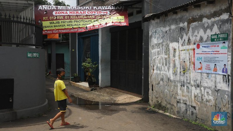 Warga melintas di wilayah Zona Merah di Kawasan Jagakarsa, Jakarta Selatan, Selasa (9/2/2021). Aturan mengenai PPKM Mikro yang berlaku mulai 9 Februari 2021 telah diterbitkan lewat Inmendagri 3 Tahun 2021. (CNBC Indonesia/Andrean Kristianto)