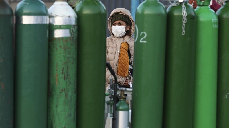 Alejandro Ccasa prays after waiting three days next to an empty oxygen tank for his uncle who has COVID-19 outside a refill shop where he is the first in line before it opens in Callao, Peru, early Tuesday, Feb. 2, 2021. Ccasa said his family has one large tank and it gives about four hours of oxygen therapy. (AP Photo/Martin Mejia)