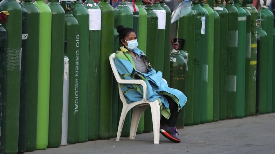 Alejandro Ccasa prays after waiting three days next to an empty oxygen tank for his uncle who has COVID-19 outside a refill shop where he is the first in line before it opens in Callao, Peru, early Tuesday, Feb. 2, 2021. Ccasa said his family has one large tank and it gives about four hours of oxygen therapy. (AP Photo/Martin Mejia)