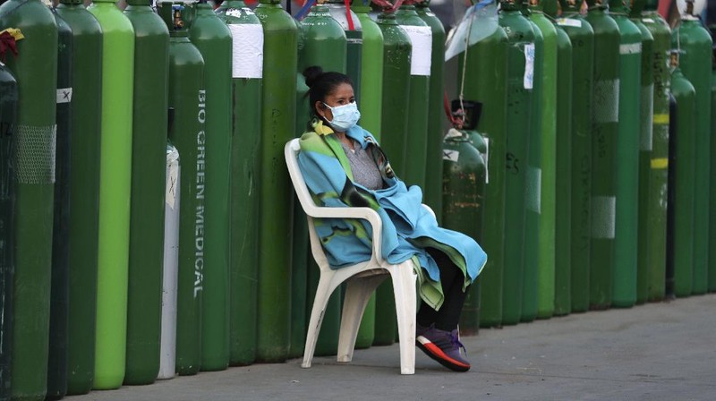 Alejandro Ccasa prays after waiting three days next to an empty oxygen tank for his uncle who has COVID-19 outside a refill shop where he is the first in line before it opens in Callao, Peru, early Tuesday, Feb. 2, 2021. Ccasa said his family has one large tank and it gives about four hours of oxygen therapy. (AP Photo/Martin Mejia)