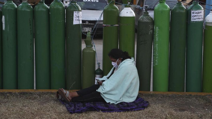 Alejandro Ccasa prays after waiting three days next to an empty oxygen tank for his uncle who has COVID-19 outside a refill shop where he is the first in line before it opens in Callao, Peru, early Tuesday, Feb. 2, 2021. Ccasa said his family has one large tank and it gives about four hours of oxygen therapy. (AP Photo/Martin Mejia)