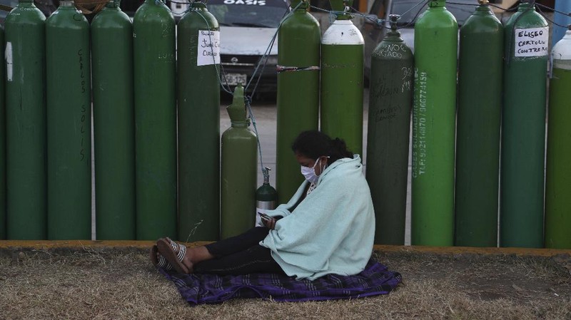 Alejandro Ccasa prays after waiting three days next to an empty oxygen tank for his uncle who has COVID-19 outside a refill shop where he is the first in line before it opens in Callao, Peru, early Tuesday, Feb. 2, 2021. Ccasa said his family has one large tank and it gives about four hours of oxygen therapy. (AP Photo/Martin Mejia)