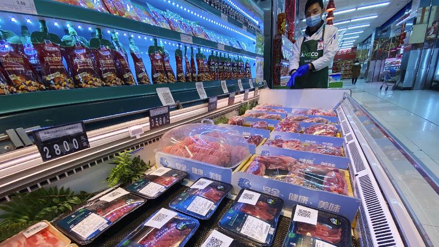 A worker wearing a mask and gloves stand near beef products from New Zealand packaged with a QR-code linked to its coronavirus test results displayed at a supermarket in Beijing, Tuesday, Nov. 24, 2020. China has stirred controversy with claims it has detected the coronavirus on packages of imported frozen food. (AP Photo/Ng Han Guan)