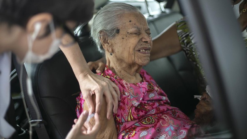 Health workers guide drivers to shots of China's Sinovac CoronaVac vaccine during a priority COVID-19 vaccination program for the elderly at a drive-thru set up in the Pacaembu soccer stadium parking lot in Sao Paulo, Brazil, Monday, Feb. 8, 2021. (AP Photo/Andre Penner)