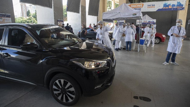 Health workers guide drivers to shots of China's Sinovac CoronaVac vaccine during a priority COVID-19 vaccination program for the elderly at a drive-thru set up in the Pacaembu soccer stadium parking lot in Sao Paulo, Brazil, Monday, Feb. 8, 2021. (AP Photo/Andre Penner)