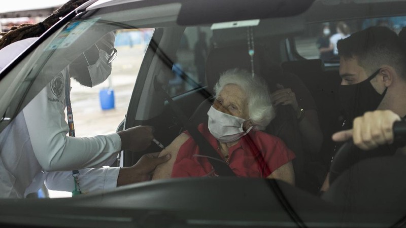 Health workers guide drivers to shots of China's Sinovac CoronaVac vaccine during a priority COVID-19 vaccination program for the elderly at a drive-thru set up in the Pacaembu soccer stadium parking lot in Sao Paulo, Brazil, Monday, Feb. 8, 2021. (AP Photo/Andre Penner)