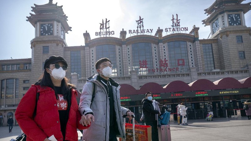 Travelers wearing face masks to protect against the coronavirus walk with their luggage outside the Beijing Railway Station in Beijing, Wednesday, Feb. 10, 2021. China appeared to be on pace for a slower than normal Lunar New Year travel rush this year after authorities discouraged people from traveling over the holiday to help maintain the nation's control over the ongoing COVID-19 pandemic. (AP Photo/Mark Schiefelbein)