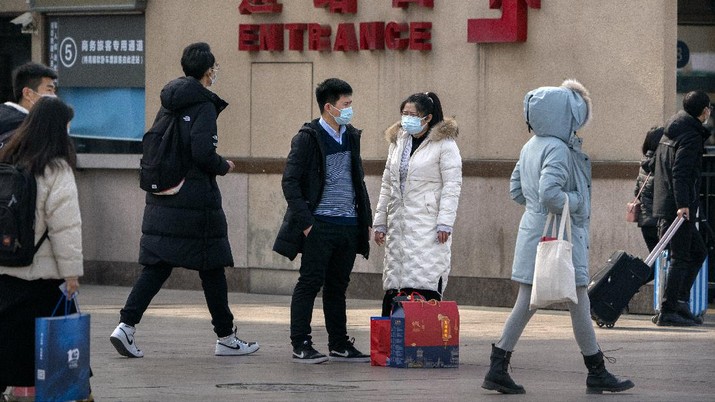 Travelers wearing face masks to protect against the coronavirus walk with their luggage outside the Beijing Railway Station in Beijing, Wednesday, Feb. 10, 2021. China appeared to be on pace for a slower than normal Lunar New Year travel rush this year after authorities discouraged people from traveling over the holiday to help maintain the nation's control over the ongoing COVID-19 pandemic. (AP Photo/Mark Schiefelbein)