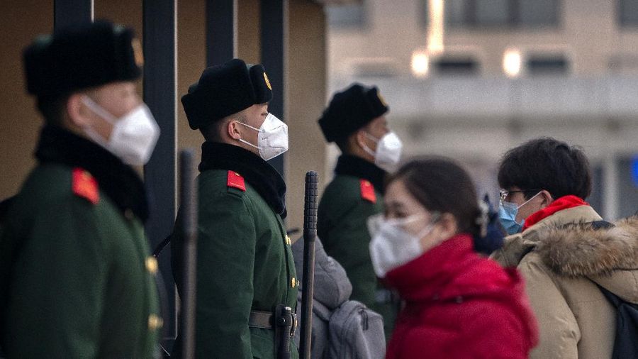 Travelers wearing face masks to protect against the coronavirus walk with their luggage outside the Beijing Railway Station in Beijing, Wednesday, Feb. 10, 2021. China appeared to be on pace for a slower than normal Lunar New Year travel rush this year after authorities discouraged people from traveling over the holiday to help maintain the nation's control over the ongoing COVID-19 pandemic. (AP Photo/Mark Schiefelbein)