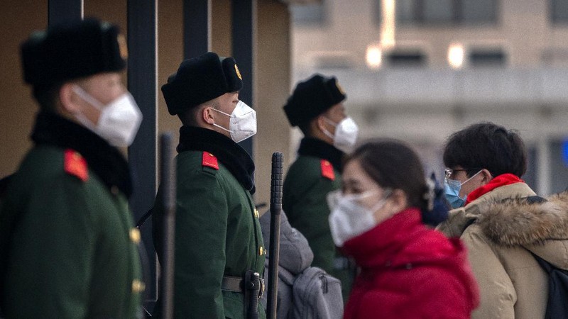 Travelers wearing face masks to protect against the coronavirus walk with their luggage outside the Beijing Railway Station in Beijing, Wednesday, Feb. 10, 2021. China appeared to be on pace for a slower than normal Lunar New Year travel rush this year after authorities discouraged people from traveling over the holiday to help maintain the nation's control over the ongoing COVID-19 pandemic. (AP Photo/Mark Schiefelbein)