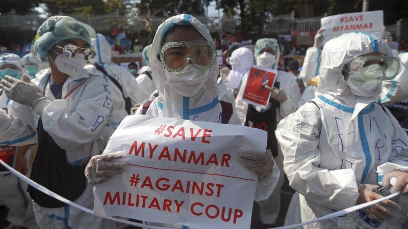 An anti-military coup protester flashes the three-fingered salute while other protesters hold placards that say 'We Don't Accept Military Coup' as they gather outside the Hledan Center in Yangon, Myanmar Saturday, Feb. 13, 2021. The daily protests in Myanmar's biggest city enters its second week despite a ban on public gatherings of five or more. (AP Photo)
