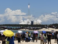 In this July 23, 2020, file photo released by China's Xinhua News Agency, spectators watch as a Long March-5 rocket carrying the Tianwen-1 Mars probe lifts off from the Wenchang Space Launch Center in southern China's Hainan Province. China is fallin
