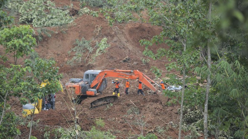 Rescuers search for victims at a village hit by a landslide in Nganjuk, East Java, Indonesia, Monday, Feb. 15, 2021. Torrential rains triggered a landslide on Indonesia's main island of Java, leaving a number of people killed or missing, as emergency personnel digging with their bare hands and farm tools desperately sought to unearth more victims on Monday, officials said. (AP Photo/Trisnadi)