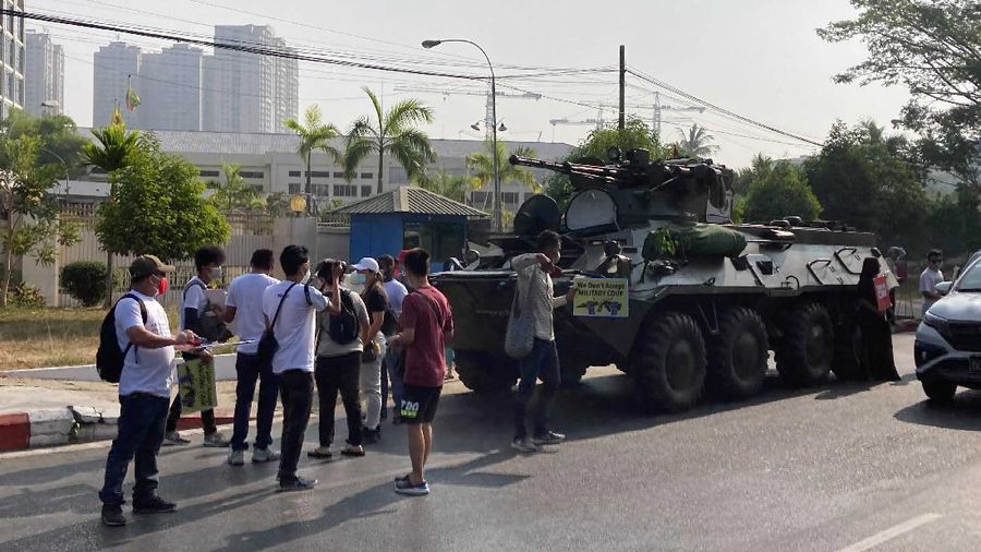 Anti-coup protesters stand in front of an armored personnel carrier deployed outside the Central Bank building in Yangon, Myanmar Monday, Feb. 15, 2021. Sightings of armored personnel carriers in Myanmar's biggest city and an internet shutdown raised political tensions late Sunday, after vast numbers of people around the country flouted orders against demonstrations to protest the military's seizure of power. (AP Photo)