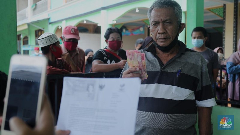 Warga menerima Bantuan Langsung Tunai (BLT) di Sawangan, Depok, Selasa (16/2/2021). Pemerintah melalui Kementerian Sosial (Kemensos) tahun ini melanjutkan penyaluran program Bantuan Sosial Tunai atau bantuan langsung tunai (BLT) secara bertahap melalui Kantor Pos. (CNBC Indonesia/Tri Susilo)
