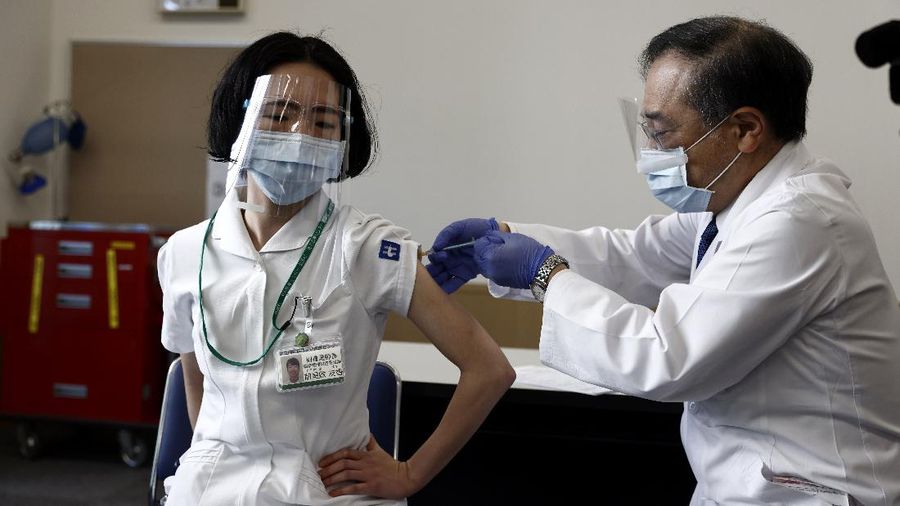 A medical worker checks the form of his colleague before giving her a dose of the COVID-19 vaccine at Tokyo Medical Center in Tokyo Wednesday, Feb. 17, 2021. Japan's first coronavirus shots were given to health workers Wednesday, beginning a vaccination campaign considered crucial to holding the already delayed Tokyo Olympics. (Behrouz Mehri/Pool Photo via AP)
