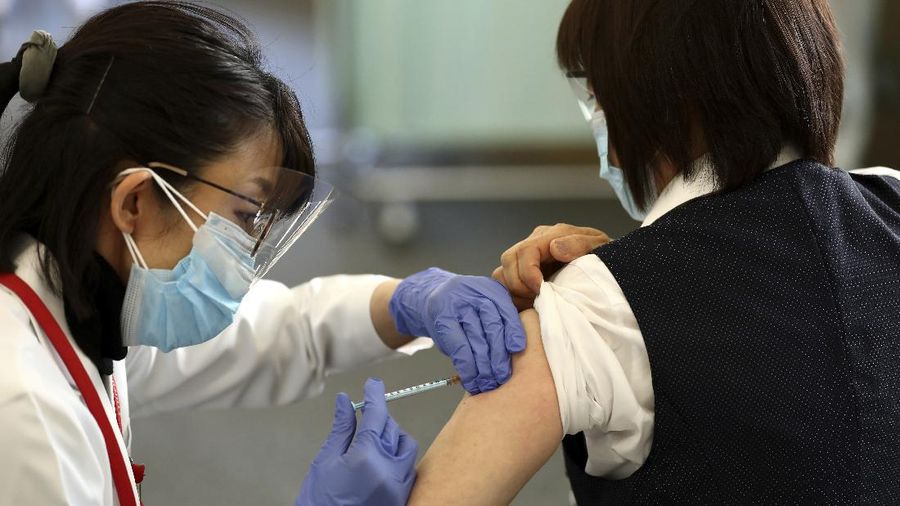 A medical worker checks the form of his colleague before giving her a dose of the COVID-19 vaccine at Tokyo Medical Center in Tokyo Wednesday, Feb. 17, 2021. Japan's first coronavirus shots were given to health workers Wednesday, beginning a vaccination campaign considered crucial to holding the already delayed Tokyo Olympics. (Behrouz Mehri/Pool Photo via AP)
