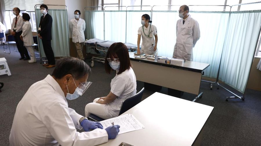 A medical worker checks the form of his colleague before giving her a dose of the COVID-19 vaccine at Tokyo Medical Center in Tokyo Wednesday, Feb. 17, 2021. Japan's first coronavirus shots were given to health workers Wednesday, beginning a vaccination campaign considered crucial to holding the already delayed Tokyo Olympics. (Behrouz Mehri/Pool Photo via AP)