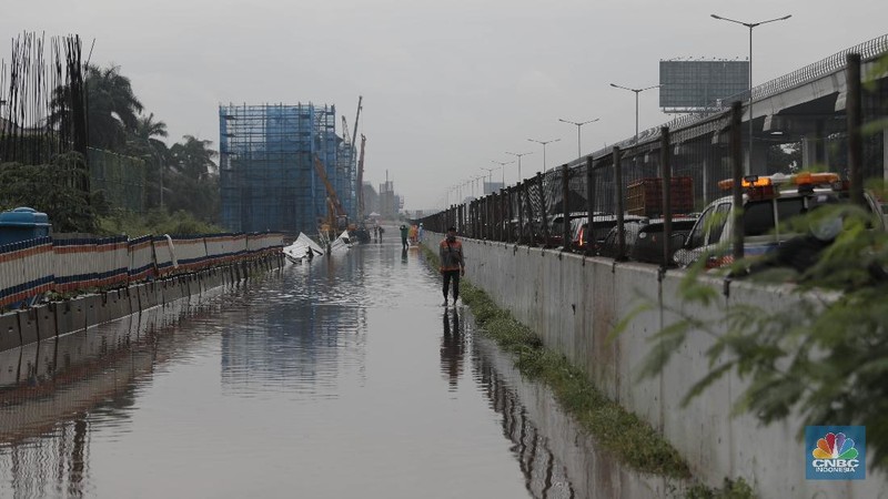 Petugas berjaga di bawah papan bertuliskan pengalihan arus karena genangan di Tol Jatibening, Jakarta, Jumat 19/2. Hujan semalaman yang mengguyur kawasan Jabodetabek membuat berbagai wilayah kebanjiran. Sejumlah kawasan tol pun terdampak banjir dan lumpuh. Akses masuk Gerbang Tol Jatibening arah Jakarta terpantau genangan. Tepatnya terjadi di lajur masuk Jatibening atau Cawang. Khusus kendaraan besar tetap dapat melintas, sementara kendaraan kecil golongan 1 dialihkan ke ruas Jalan Tol Dalam Kota. (CNBC Indonesia/ Muhammad Sabki)