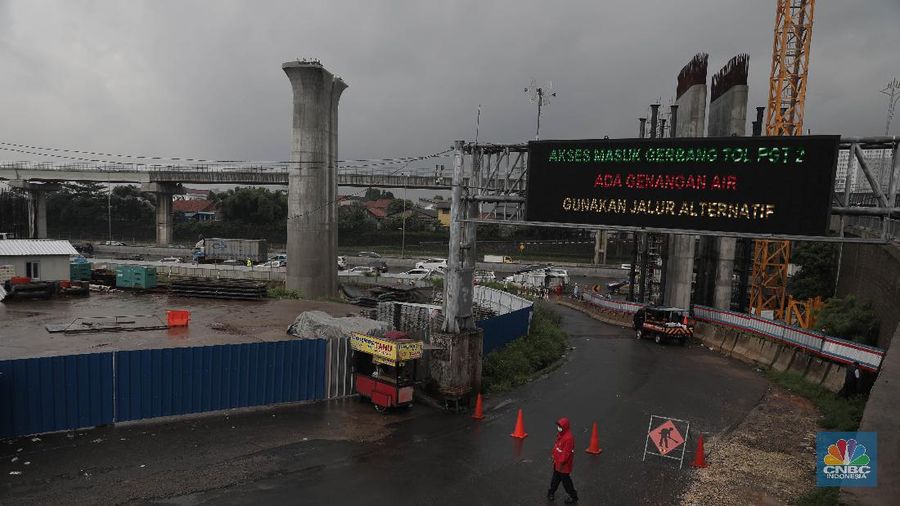 Petugas berjaga di bawah papan bertuliskan pengalihan arus karena genangan di Tol Jatibening, Jakarta, Jumat 19/2. Hujan semalaman yang mengguyur kawasan Jabodetabek membuat berbagai wilayah kebanjiran. Sejumlah kawasan tol pun terdampak banjir dan lumpuh. Akses masuk Gerbang Tol Jatibening arah Jakarta terpantau genangan. Tepatnya terjadi di lajur masuk Jatibening atau Cawang. Khusus kendaraan besar tetap dapat melintas, sementara kendaraan kecil golongan 1 dialihkan ke ruas Jalan Tol Dalam Kota. (CNBC Indonesia/ Muhammad Sabki)