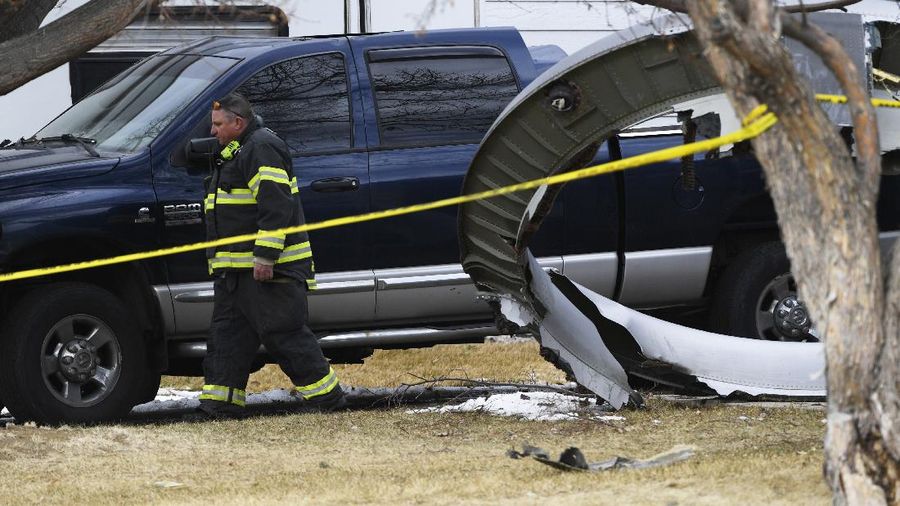 A North Metro firefighter walks past a large piece of an airplane engine in the front yard of a home on Elmwood Street near E. 13th Avenue, Saturday, Feb. 20, 2021, in Broomfield, Colo. Debris from a United Airlines plane fell onto Denver suburbs during an emergency landing Saturday after one of its engines suffered a catastrophic failure and rained pieces of the engine casing on a neighborhood where it narrowly missed a home. (Andy Cross/The Denver Post via AP)