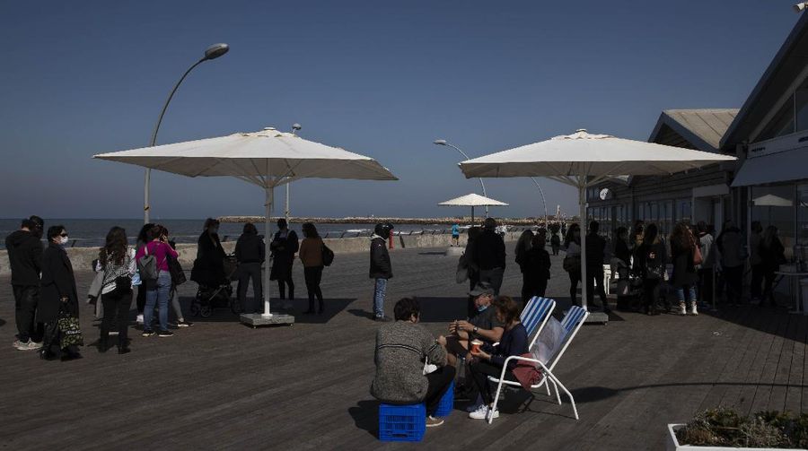Israelis wait in line at a store at the port, in Tel Aviv, Israel, Sunday, Feb. 21, 2021. Israel lifted many of its coronavirus restrictions and started reopening its economy Sunday as the country's vaccination drive and third nationwide lockdown have started to bring down infections. (AP Photo/Sebastian Scheiner)