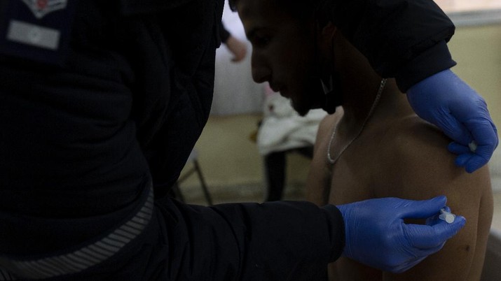 Virus Outbreak Israel Palestinians A Palestinian man sits as ea medic with the Magen David Adom emergency service administers a dose of the Pfizer-BioNTech COVID-19 vaccine during a one-day clinic at a school near the Al Aqsa Mosque compound to vaccinate worshippers following Friday prayers in the Old City of Jerusalem, Friday, Feb. 19, 2021. (AP Photo/Maya Alleruzzo)