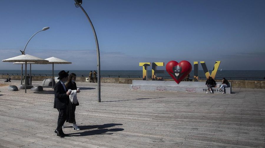 Israelis walk at the port in Tel Aviv, Israel, Sunday, Feb. 21, 2021. Israel lifted many of its coronavirus restrictions and started reopening its economy Sunday as the country's vaccination drive and third nationwide lockdown have started to bring down infections. (AP Photo/Sebastian Scheiner)