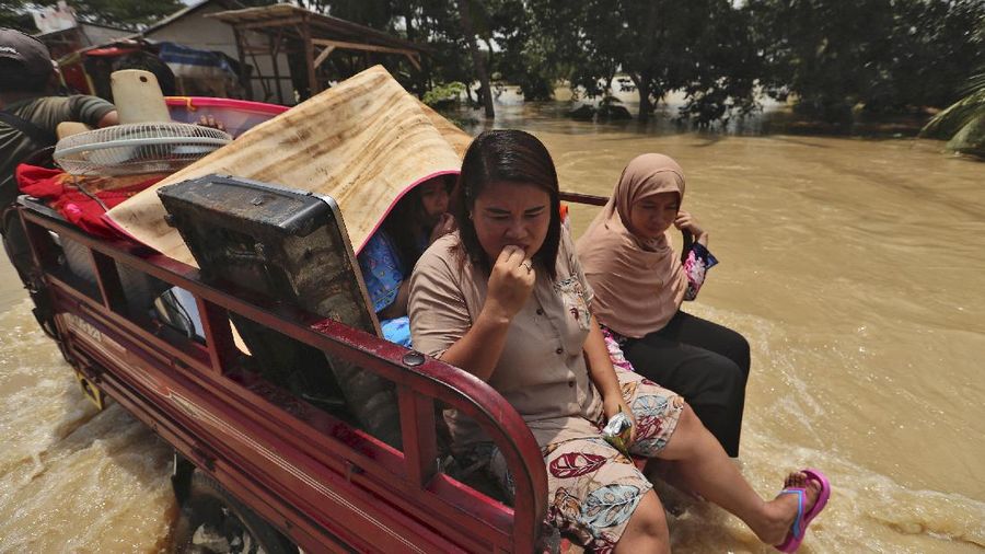Indonesian youths play in the water during a flood in Bekasi, Indonesia, Monday, Feb. 22, 2021. Thousands of residents are being evacuated on the outskirts of Indonesia's capital amid flooding after the Citarum River embankment broke, officials said Monday. (AP Photo/Achmad Ibrahim)