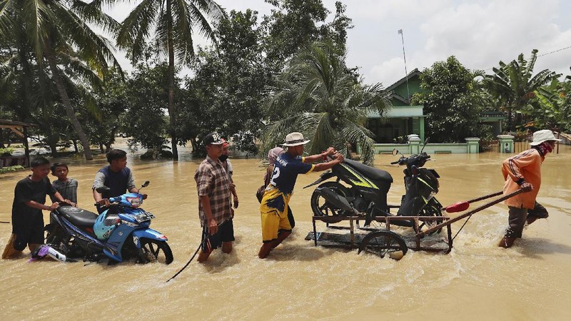 Indonesian youths play in the water during a flood in Bekasi, Indonesia, Monday, Feb. 22, 2021. Thousands of residents are being evacuated on the outskirts of Indonesia's capital amid flooding after the Citarum River embankment broke, officials said Monday. (AP Photo/Achmad Ibrahim)