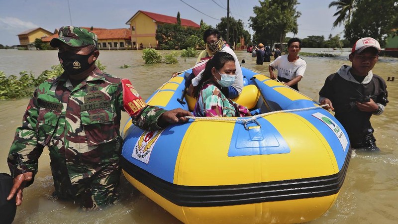 Indonesian youths play in the water during a flood in Bekasi, Indonesia, Monday, Feb. 22, 2021. Thousands of residents are being evacuated on the outskirts of Indonesia's capital amid flooding after the Citarum River embankment broke, officials said Monday. (AP Photo/Achmad Ibrahim)