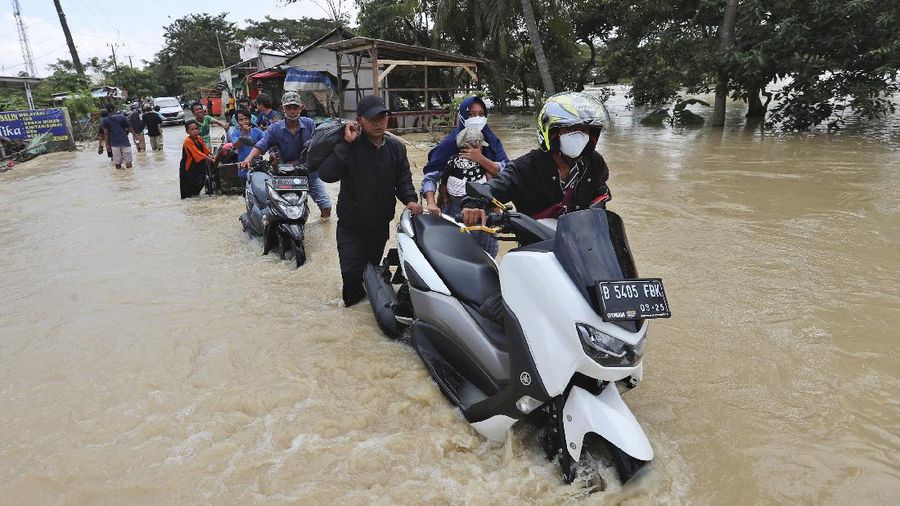 Indonesian youths play in the water during a flood in Bekasi, Indonesia, Monday, Feb. 22, 2021. Thousands of residents are being evacuated on the outskirts of Indonesia's capital amid flooding after the Citarum River embankment broke, officials said Monday. (AP Photo/Achmad Ibrahim)