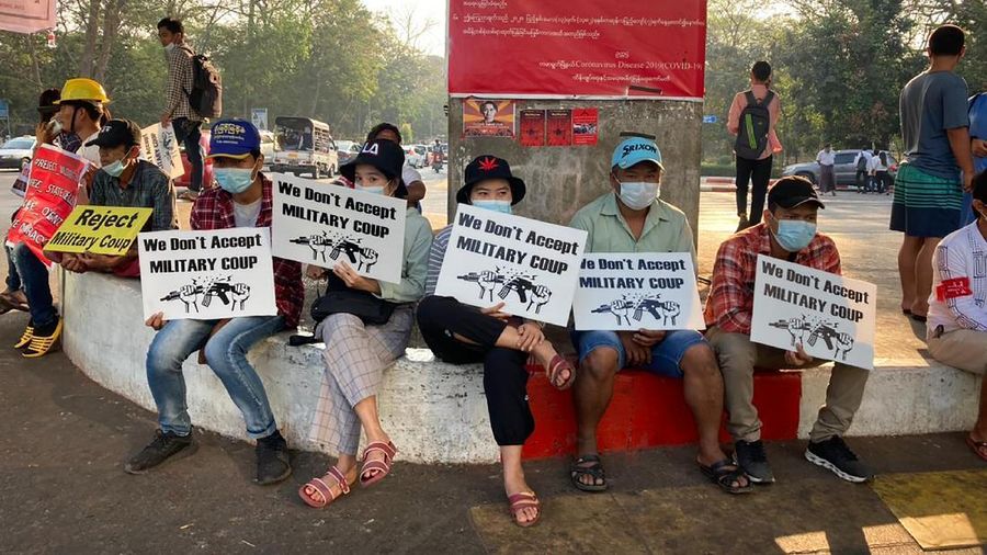 Anti-coup protesters hold signs that read 