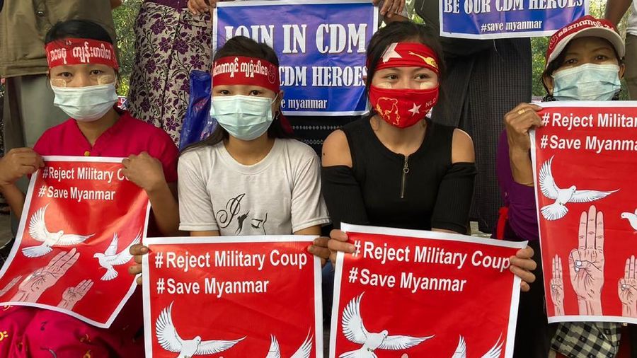 Anti-coup protesters hold signs that read 