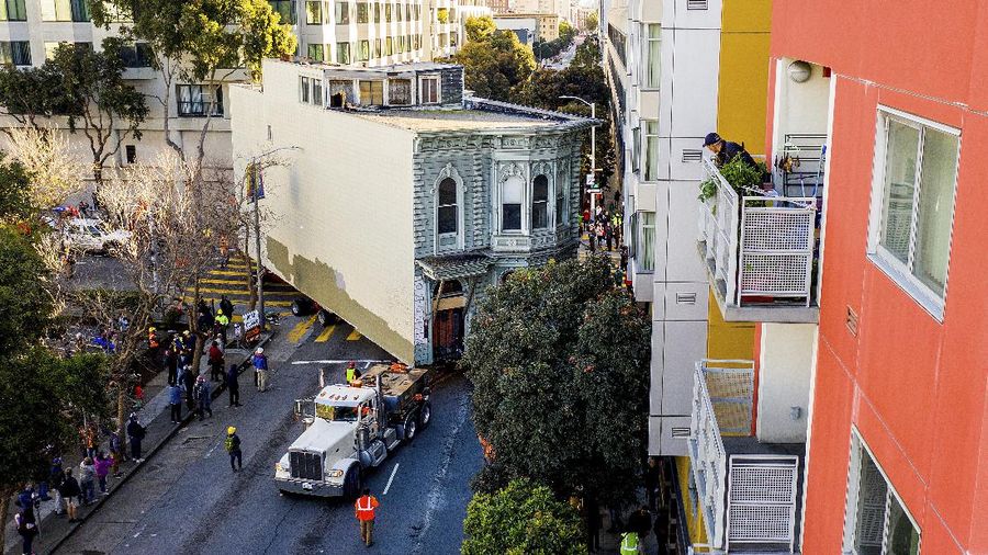 CORRECTS APPROXIMATE COST TO $400,000, INTEAD OF $200,000 - Crowds watch as a truck pulls a Victorian home through San Francisco on Sunday, Feb. 21, 2021. The house, built in 1882, was moved to a new location about six blocks away to make room for a condominium development. According to the consultant overseeing the project, the move cost approximately $400,000 and involved removing street lights, parking meters, and utility lines. (AP Photo/Noah Berger)