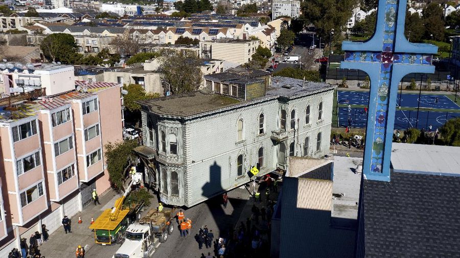 CORRECTS APPROXIMATE COST TO $400,000, INTEAD OF $200,000 - Crowds watch as a truck pulls a Victorian home through San Francisco on Sunday, Feb. 21, 2021. The house, built in 1882, was moved to a new location about six blocks away to make room for a condominium development. According to the consultant overseeing the project, the move cost approximately $400,000 and involved removing street lights, parking meters, and utility lines. (AP Photo/Noah Berger)