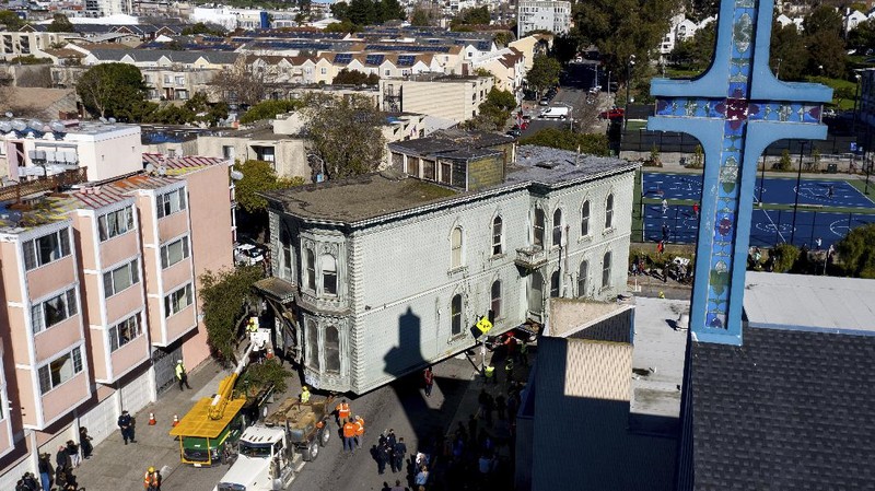 CORRECTS APPROXIMATE COST TO $400,000, INTEAD OF $200,000 - Crowds watch as a truck pulls a Victorian home through San Francisco on Sunday, Feb. 21, 2021. The house, built in 1882, was moved to a new location about six blocks away to make room for a condominium development. According to the consultant overseeing the project, the move cost approximately $400,000 and involved removing street lights, parking meters, and utility lines. (AP Photo/Noah Berger)