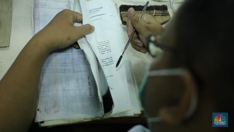 Petugas restorasi ARSIP Nasional Republik Indonesia (ANRI) melakukan perbaikan dokumen milik warga yang terdampak banjir, Jakarta, Senin ( 22/2/2021). Dokumen yang rusak seperti Ijazah hingga akte kelahiran akan diperbaiki 1 sampai 4 Minggu. Contoh arsip keluarga yang bisa diperbaiki dari kerusakan banjir adalah akte, surat perkawinan, akte kelahiran, surat kematian, STTB dll. Maksimal berkas yang diterima 10 lembar.  (CNBC Indonesia/ Tri Susilo)