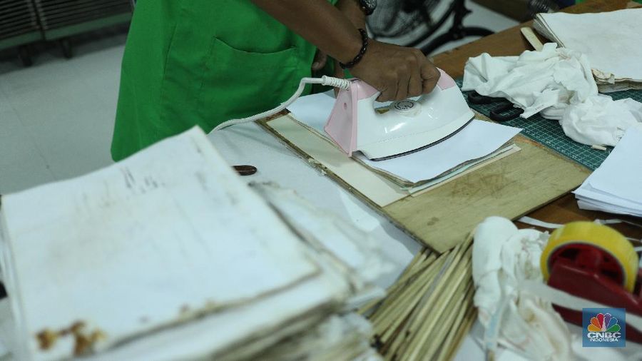 Petugas restorasi ARSIP Nasional Republik Indonesia (ANRI) melakukan perbaikan dokumen milik warga yang terdampak banjir, Jakarta, Senin ( 22/2/2021). Dokumen yang rusak seperti Ijazah hingga akte kelahiran akan diperbaiki 1 sampai 4 Minggu. Contoh arsip keluarga yang bisa diperbaiki dari kerusakan banjir adalah akte, surat perkawinan, akte kelahiran, surat kematian, STTB dll. Maksimal berkas yang diterima 10 lembar.  (CNBC Indonesia/ Tri Susilo)