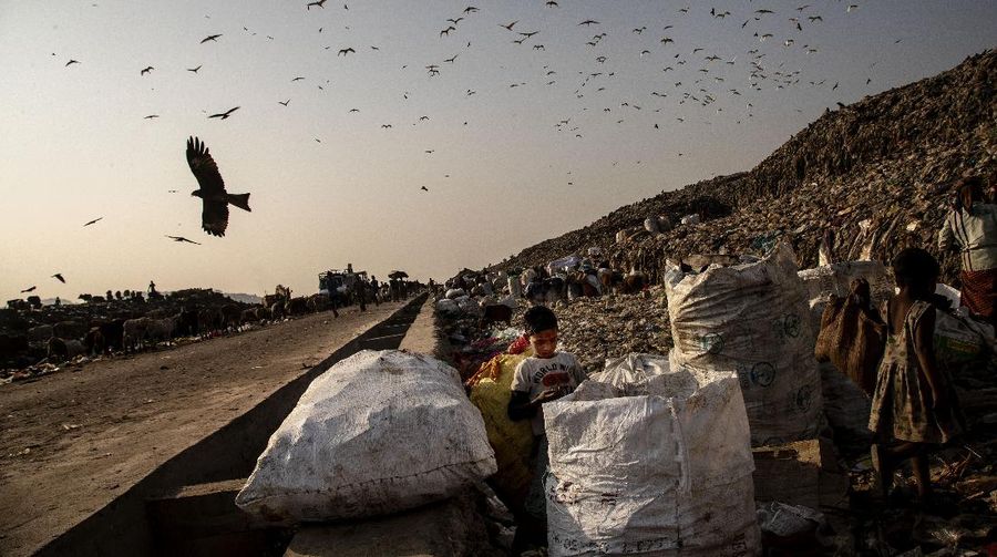 Imradul Ali, 10, left, and his mother Anuwara Beghum, 30, take a break as they look for recyclable material at a landfill on the outskirts of Gauhati, India, Thursday, Feb. 4, 2021. Once school is done for the day, Ali, rushes home to change out of his uniform so that he can start his job as a scavenger in India’s remote northeast. Coming from a family of scavengers or “rag pickers,