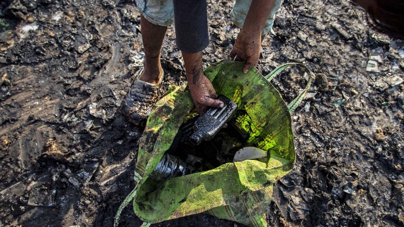 Imradul Ali, 10, left, and his mother Anuwara Beghum, 30, take a break as they look for recyclable material at a landfill on the outskirts of Gauhati, India, Thursday, Feb. 4, 2021. Once school is done for the day, Ali, rushes home to change out of his uniform so that he can start his job as a scavenger in India’s remote northeast. Coming from a family of scavengers or “rag pickers,