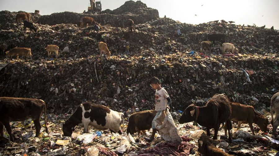 Imradul Ali, 10, left, and his mother Anuwara Beghum, 30, take a break as they look for recyclable material at a landfill on the outskirts of Gauhati, India, Thursday, Feb. 4, 2021. Once school is done for the day, Ali, rushes home to change out of his uniform so that he can start his job as a scavenger in India’s remote northeast. Coming from a family of scavengers or “rag pickers,